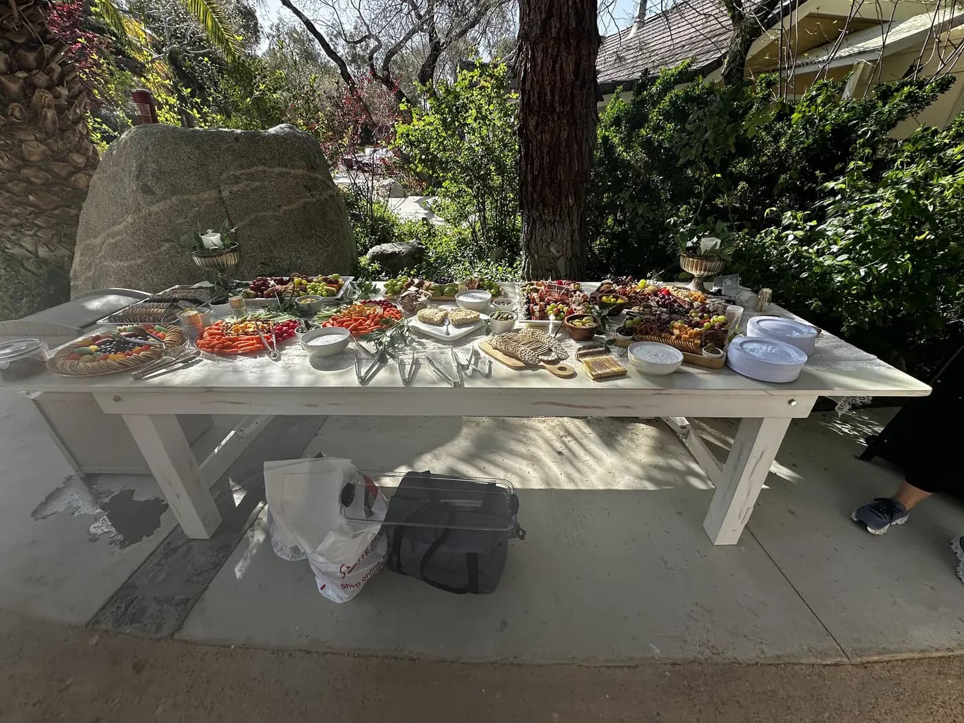 A food spread on a farmhouse table in the shade