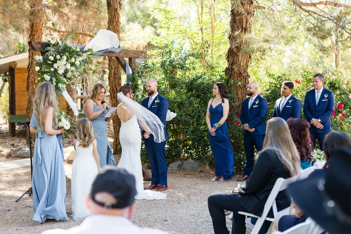 An outdoor ceremony in progress at the floral arch at The Garden