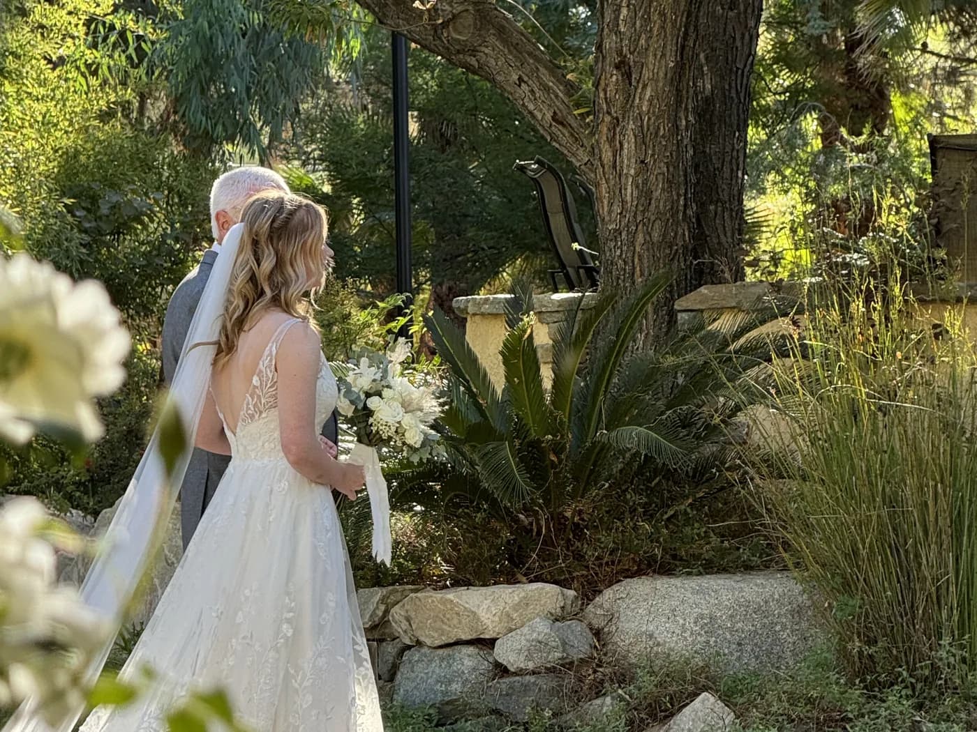A bride and her father waiting in the garden before walking down the aisle