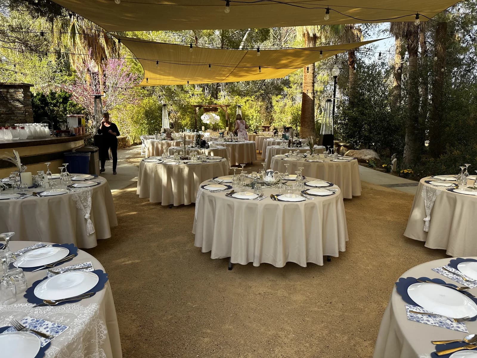 Round tables dressed in linen under the sail shades